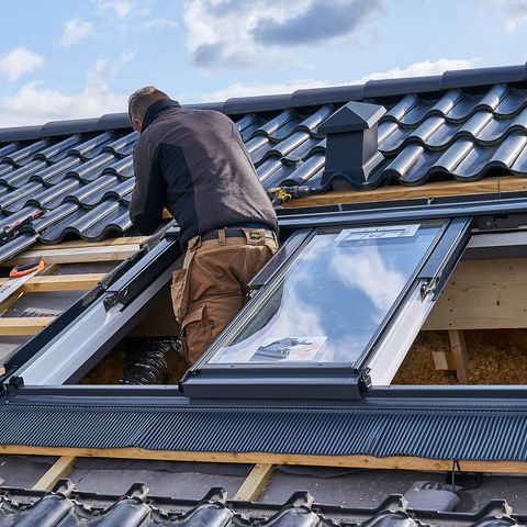Dachdecker beim professionellen Einbau eines neuen Velux Dachfensters auf dunklem Ziegeldach